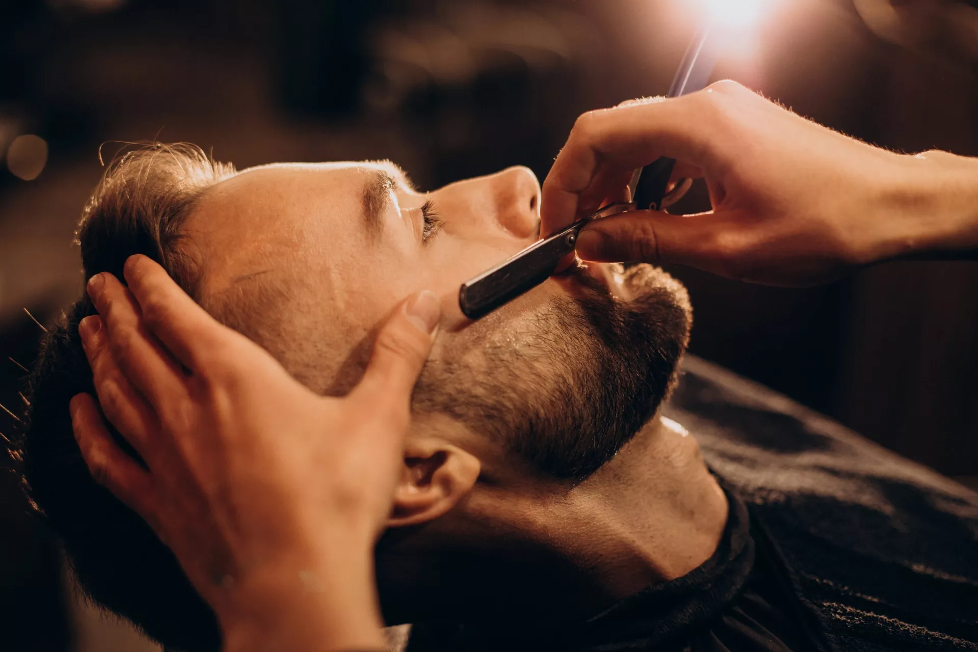 Hombre mientras le cortan la barba con navaja