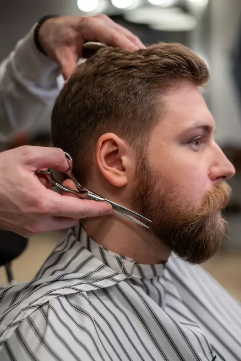 Hombre de perfil mientra le arreglan el pelo y la barba