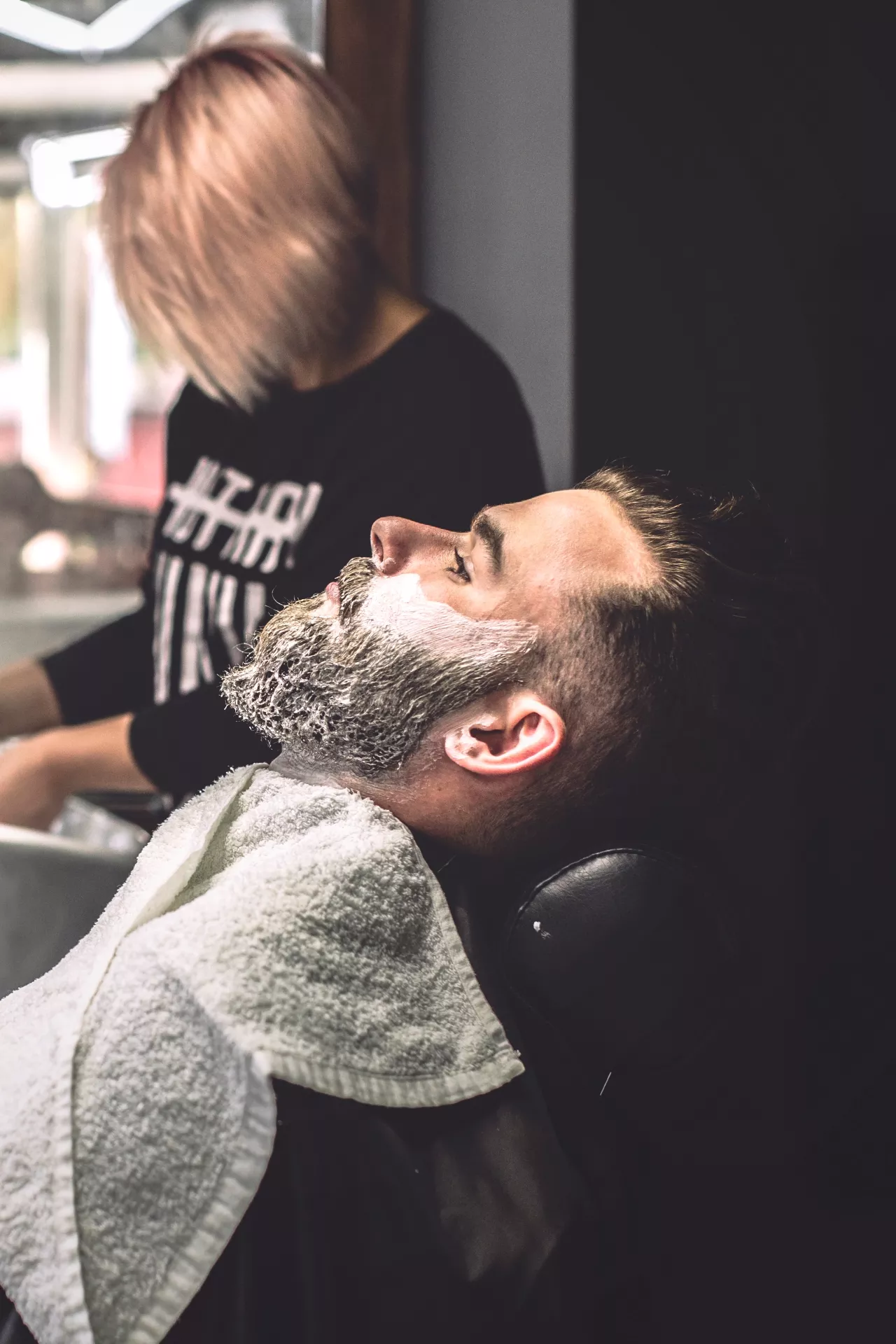 Hombre recostado en un sofá de barbería con espuma en la cara