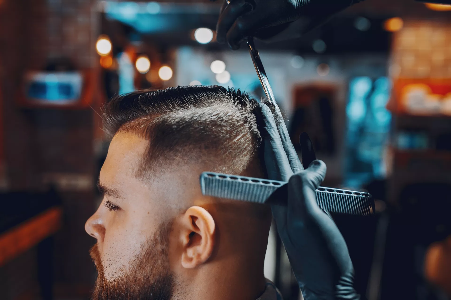 Hombre mientras le sujetan el pelo con los dedos para cortarlo