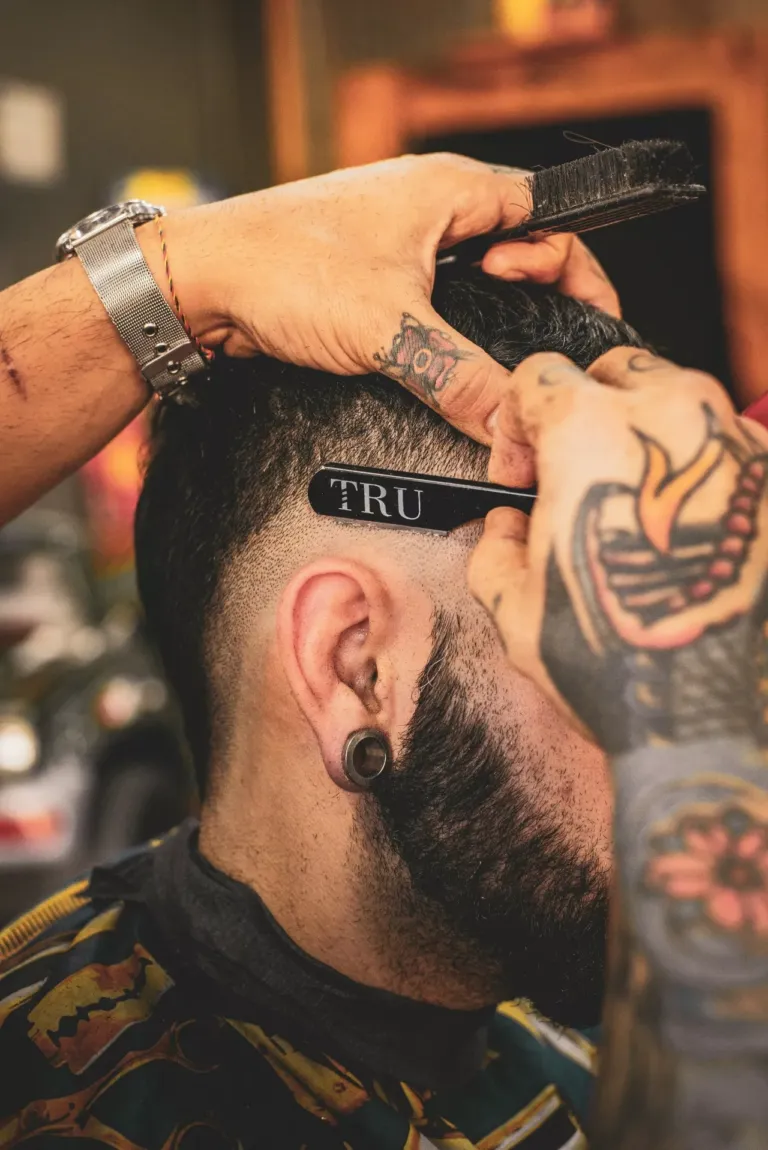 Hombre mientras le hacen un corte de pelo con navaja