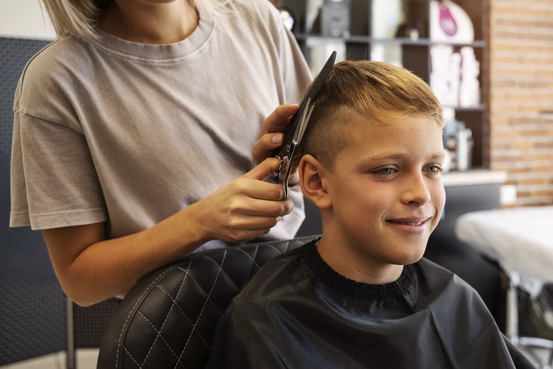 Manos sujetando tijeras y peine mientras cortan el pelo a un niño