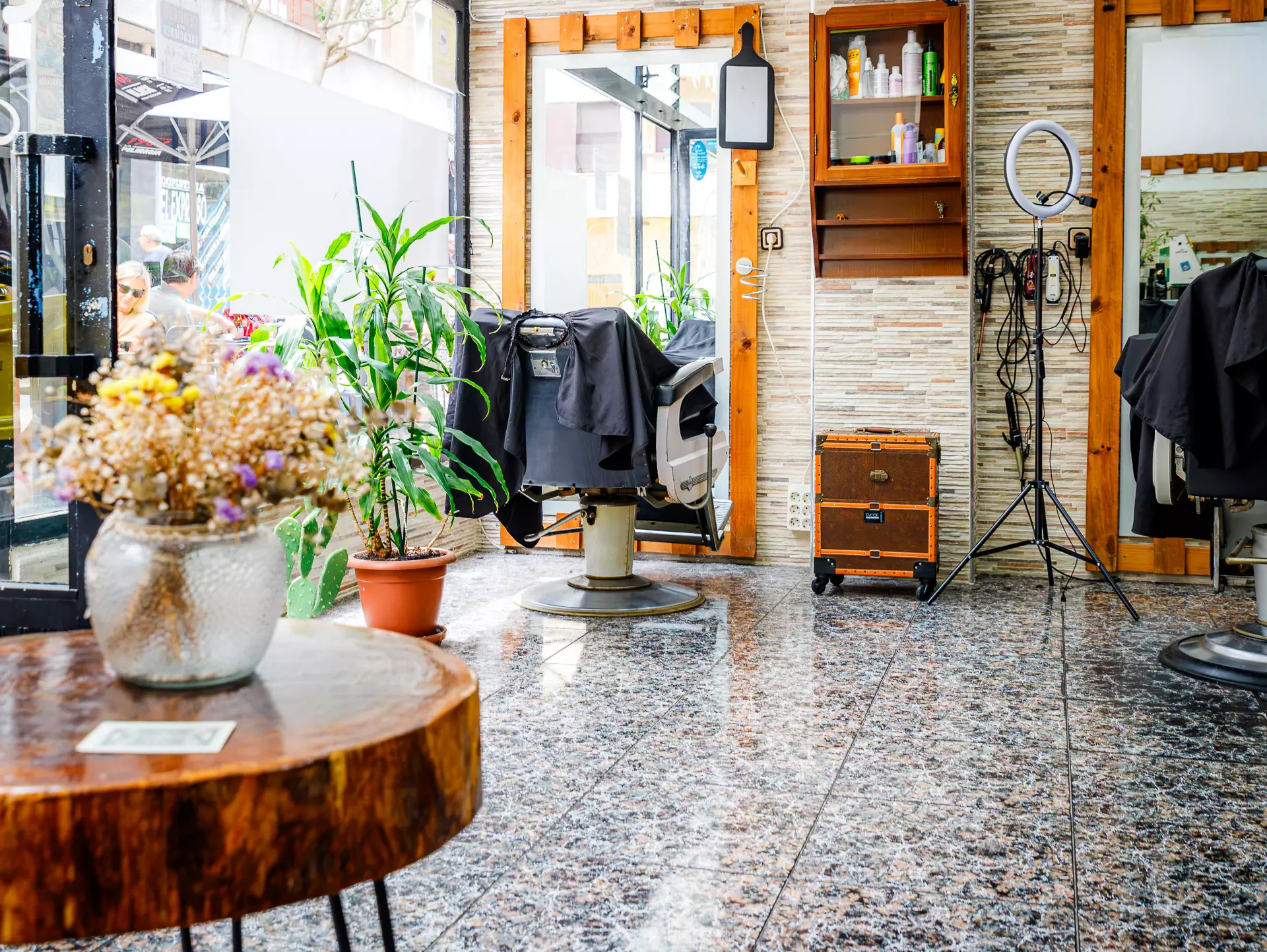 Vista general del salón de peluquería con un sillón, un espejo grande, y diversas herramientas como maquinilla, espejos de mano...